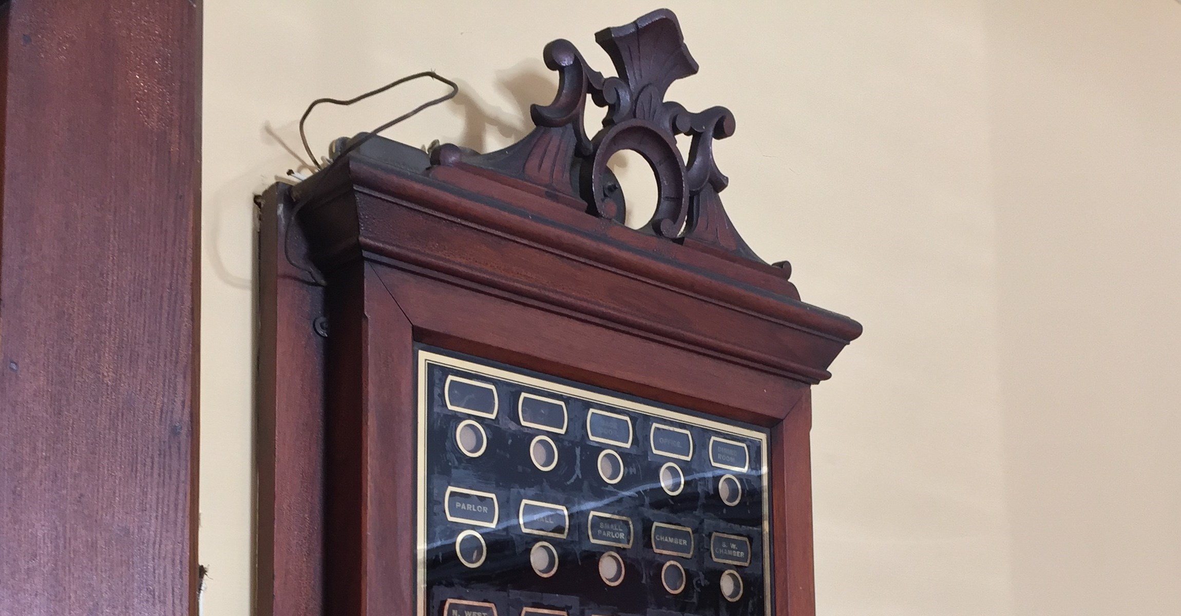 Decorative dark wood frame around black panel with labels of rooms with circles under each one.