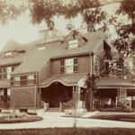Sepia toned photograph of a three story house with shingles.